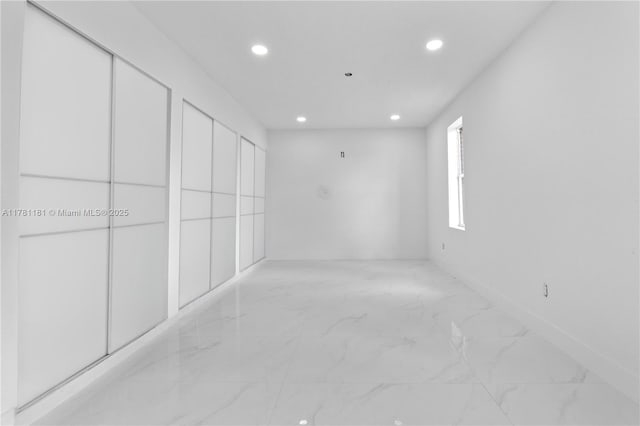 spare room with recessed lighting, marble finish floor, and baseboards