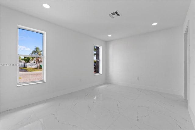 empty room featuring visible vents, baseboards, marble finish floor, and a healthy amount of sunlight