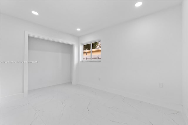 unfurnished room featuring marble finish floor, baseboards, and recessed lighting