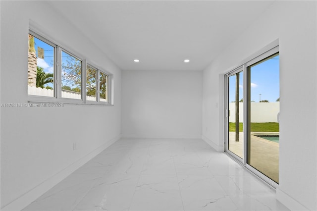 unfurnished room with recessed lighting, plenty of natural light, marble finish floor, and baseboards