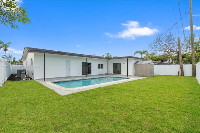back of property featuring an outdoor structure, stucco siding, a fenced backyard, and a storage unit