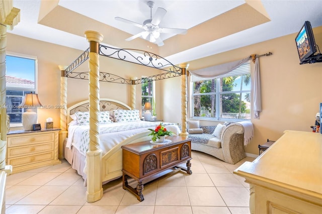 bedroom featuring light tile patterned floors, a tray ceiling, and a ceiling fan