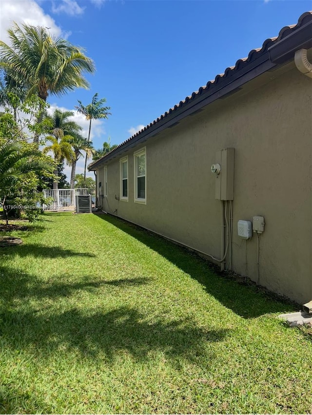 view of yard featuring central AC and fence