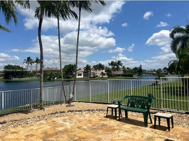 view of patio / terrace featuring a water view and fence