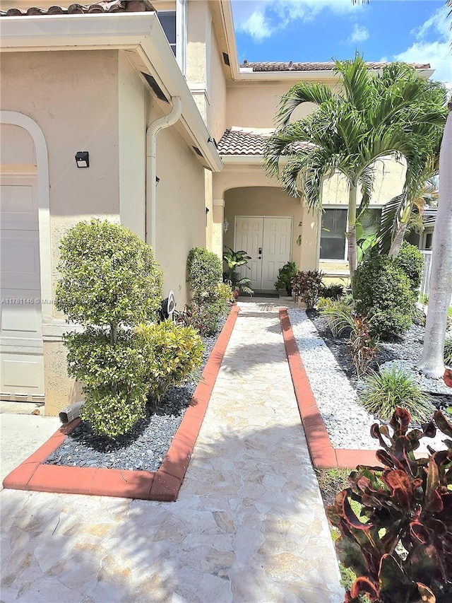 doorway to property featuring a tile roof and stucco siding
