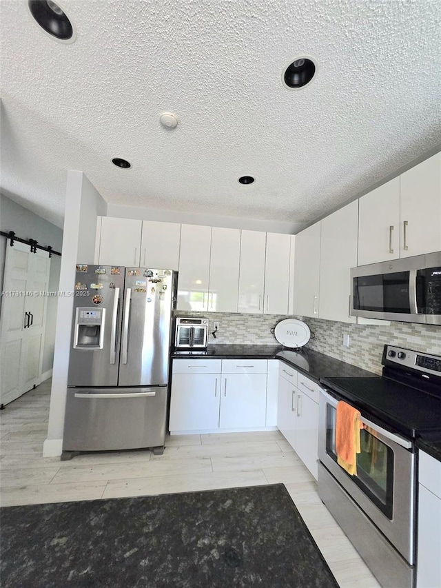 kitchen with dark countertops, decorative backsplash, white cabinetry, and stainless steel appliances