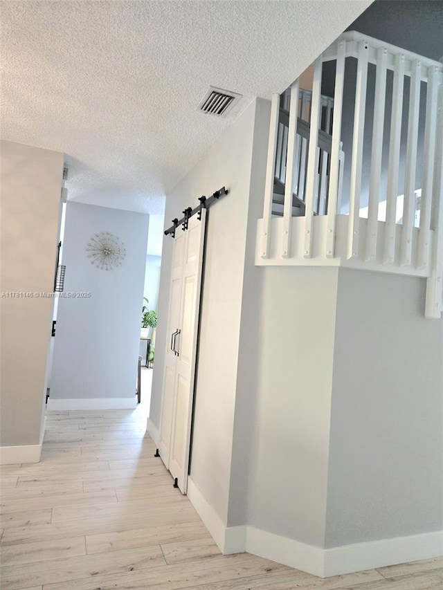 hallway with visible vents, baseboards, and wood finished floors