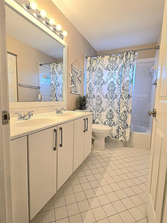 bathroom with toilet, tile patterned floors, double vanity, and a sink