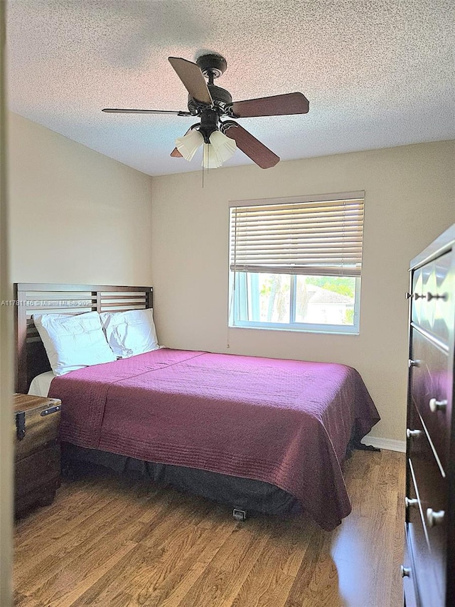 bedroom with a textured ceiling, wood finished floors, and a ceiling fan