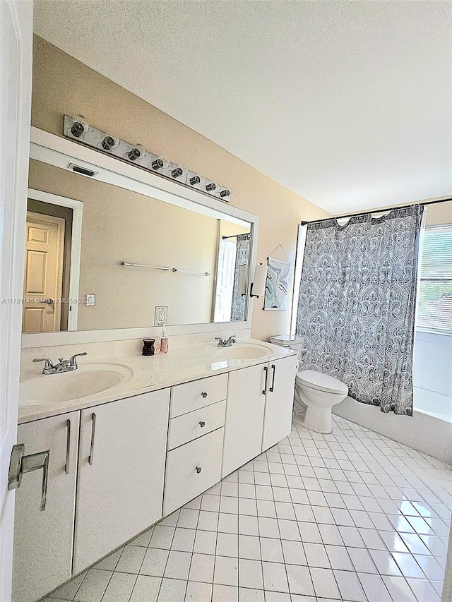 full bath with toilet, tile patterned floors, double vanity, and a sink