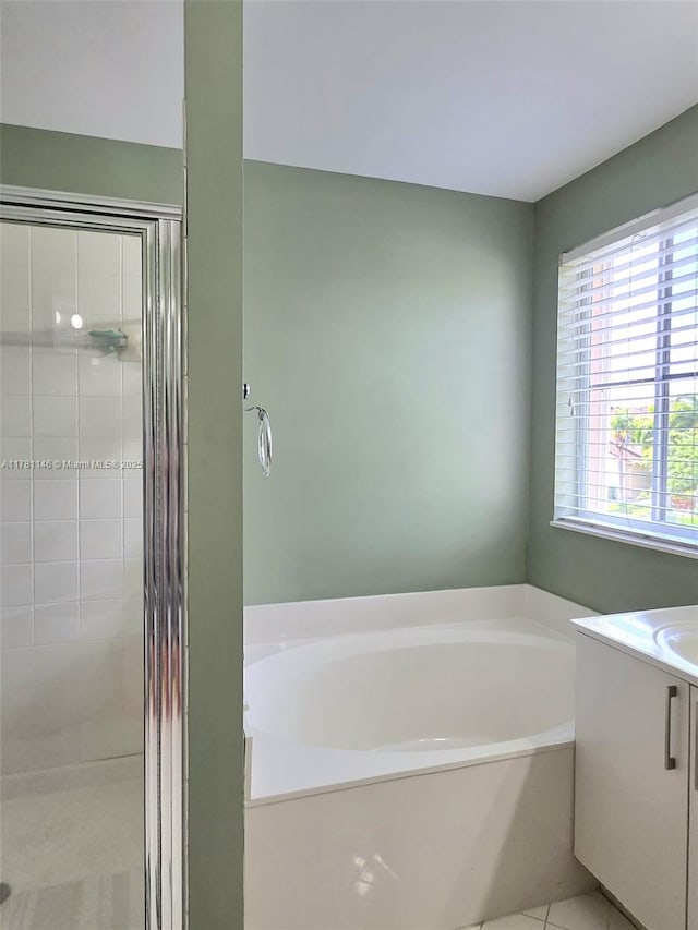 bathroom featuring tile patterned flooring, vanity, a bath, and a stall shower