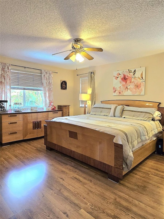bedroom with a textured ceiling, wood finished floors, and ceiling fan