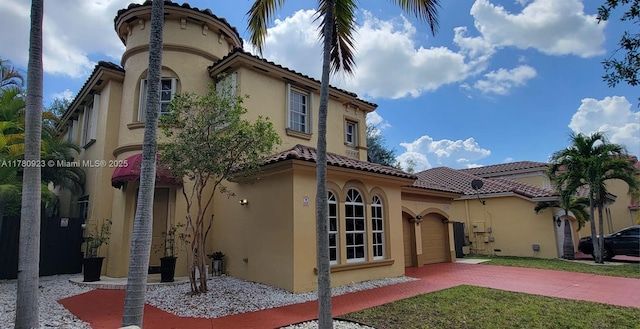 exterior space featuring stucco siding, driveway, a tiled roof, and a front yard