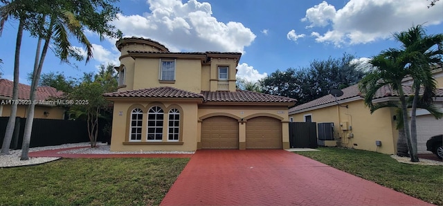 mediterranean / spanish-style home featuring fence, stucco siding, decorative driveway, and a front yard