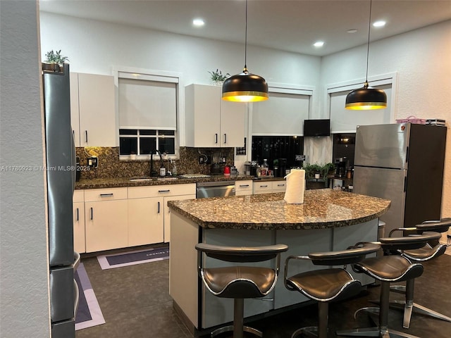 kitchen featuring a sink, appliances with stainless steel finishes, decorative backsplash, and a breakfast bar area