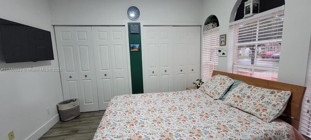 bedroom with baseboards, multiple closets, and wood finished floors