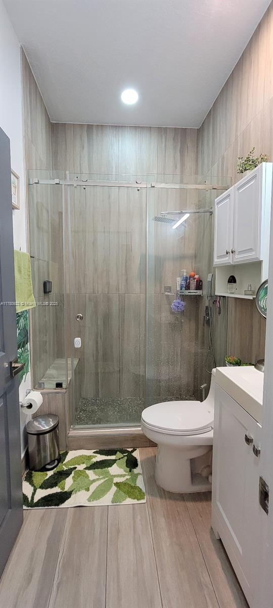 bathroom featuring vanity, a stall shower, wood finished floors, and toilet