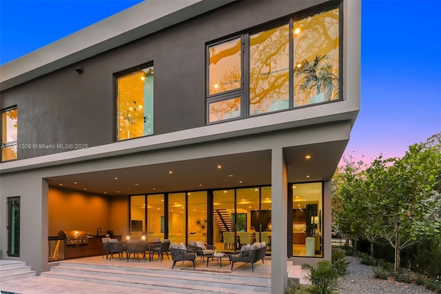 2851 W Trade Ave, Miami, FL 33133 - back of property at dusk featuring a patio, an outdoor hangout area, and stucco siding