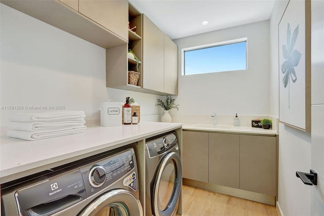 2851 W Trade Ave, Miami, FL 33133 - washroom with light wood-style floors, a sink, cabinet space, and washer and clothes dryer