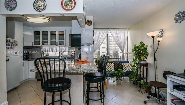 17011 N Bay Rd Unit 701, Sunny Isles Beach, FL 33160 - kitchen with glass insert cabinets, freestanding refrigerator, white cabinetry, and light tile patterned floors