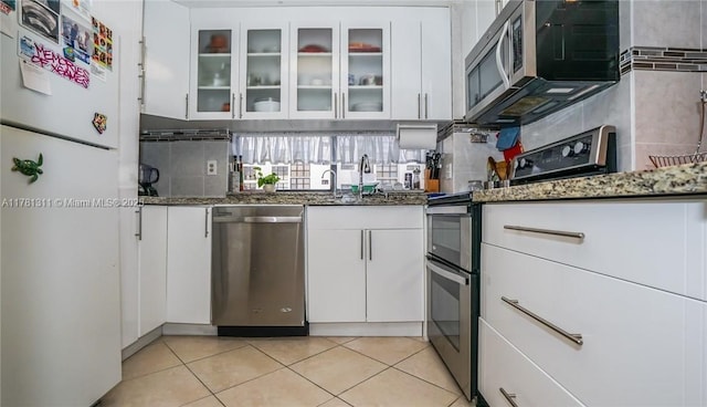 17011 N Bay Rd Unit 701, Sunny Isles Beach, FL 33160 - kitchen with dark stone countertops, white cabinetry, glass insert cabinets, and stainless steel appliances