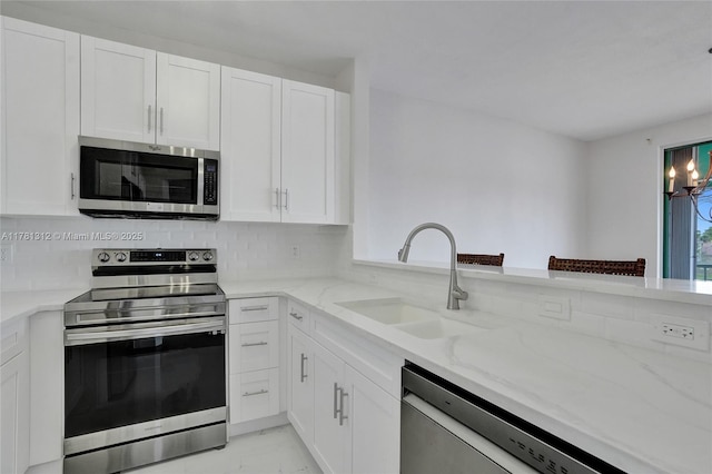 kitchen with light stone counters, a sink, marble finish floor, stainless steel appliances, and white cabinetry