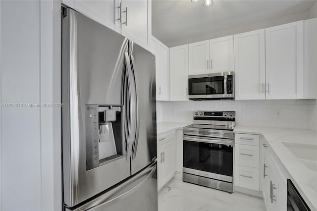 kitchen featuring marble finish floor, appliances with stainless steel finishes, light stone countertops, and white cabinetry