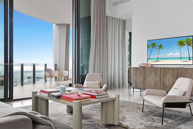 living room with a view of the beach, expansive windows, and visible vents