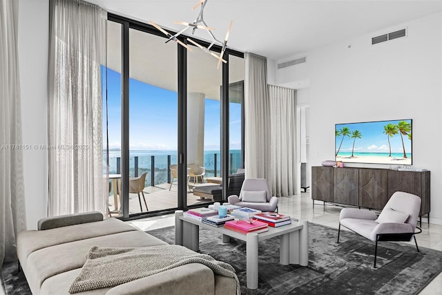 living room featuring a notable chandelier, a towering ceiling, visible vents, and floor to ceiling windows
