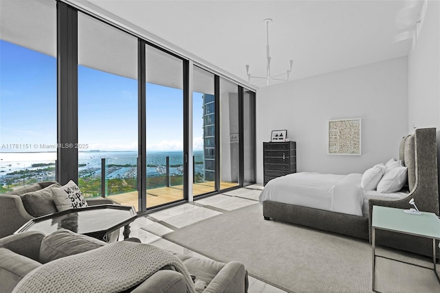 bedroom with an inviting chandelier, expansive windows, access to outside, and a water view
