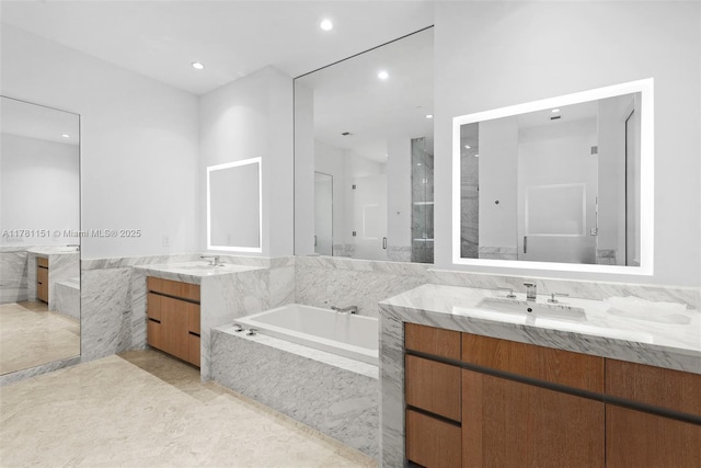 full bath with a garden tub, two vanities, a sink, and recessed lighting