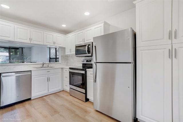 3950 Cocoplum Cir Unit F, Coconut Creek, FL 33063 - kitchen with appliances with stainless steel finishes, a sink, light wood-style floors, white cabinetry, and recessed lighting