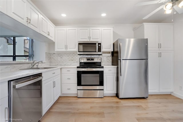 3950 Cocoplum Cir Unit F, Coconut Creek, FL 33063 - kitchen with appliances with stainless steel finishes, white cabinets, tasteful backsplash, a ceiling fan, and light wood-style flooring