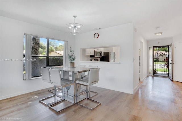 3950 Cocoplum Cir Unit F, Coconut Creek, FL 33063 - dining room featuring a chandelier, light wood-type flooring, and baseboards