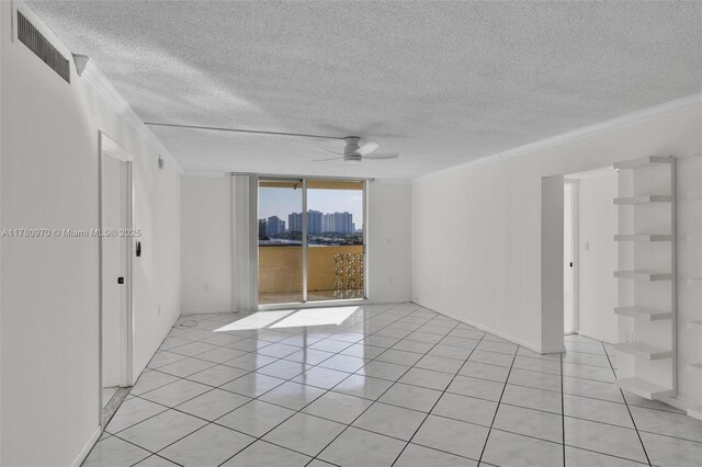 spare room with visible vents, a view of city, ornamental molding, a ceiling fan, and expansive windows