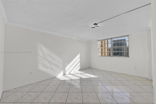 spare room featuring a textured ceiling, light tile patterned floors, and crown molding