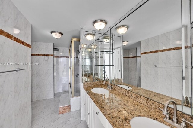 full bathroom with double vanity, a tile shower, and a sink