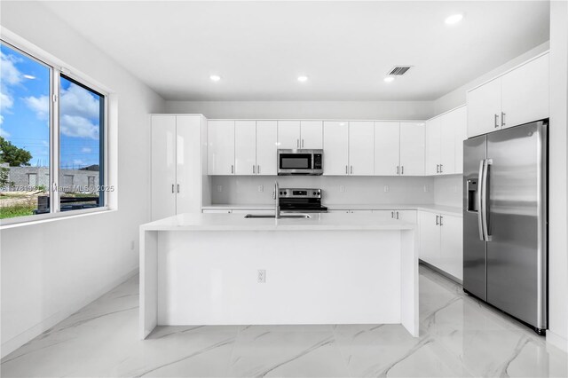 kitchen featuring light countertops, marble finish floor, a sink, and appliances with stainless steel finishes