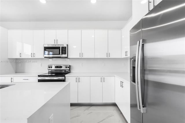 kitchen with light countertops, white cabinetry, marble finish floor, and stainless steel appliances