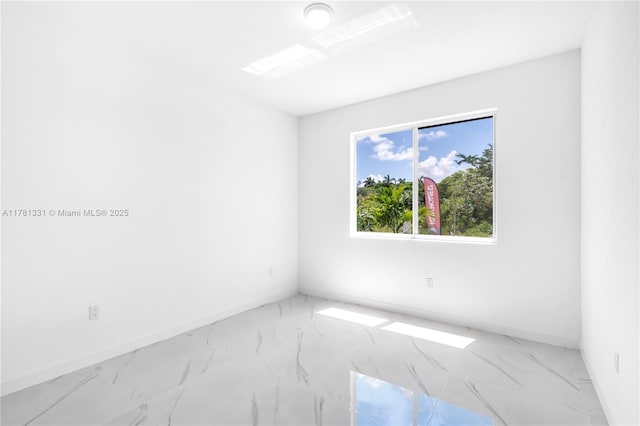 empty room featuring marble finish floor and baseboards