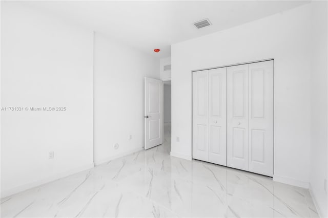 unfurnished bedroom with visible vents, marble finish floor, and a closet