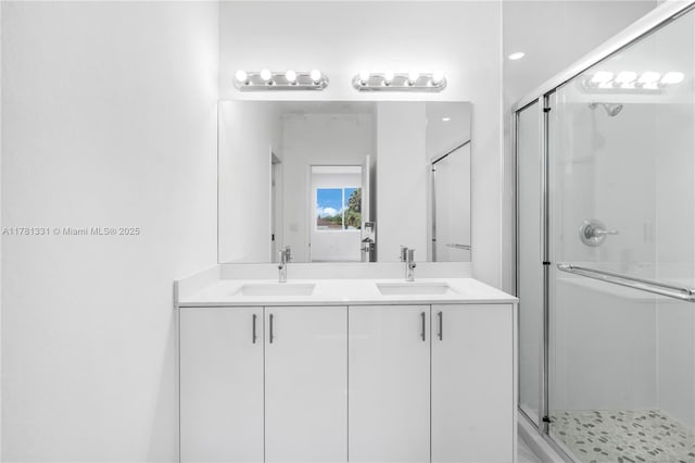 bathroom with a stall shower, double vanity, and a sink