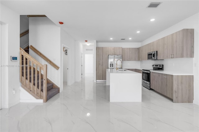 kitchen featuring light countertops, visible vents, modern cabinets, a center island with sink, and stainless steel appliances