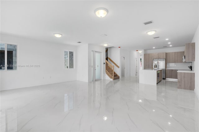 unfurnished living room featuring stairway, visible vents, and marble finish floor