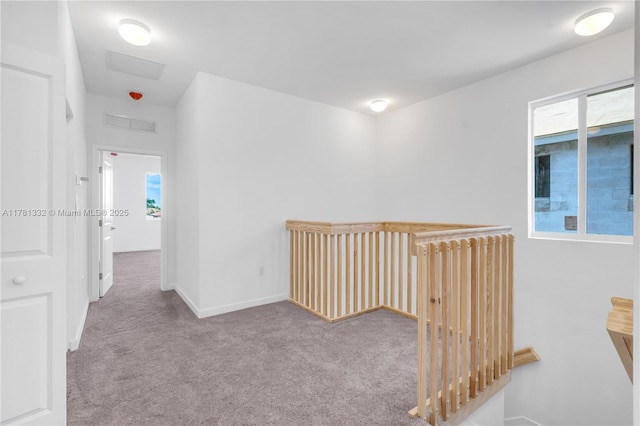 corridor featuring visible vents, a wealth of natural light, carpet, and baseboards