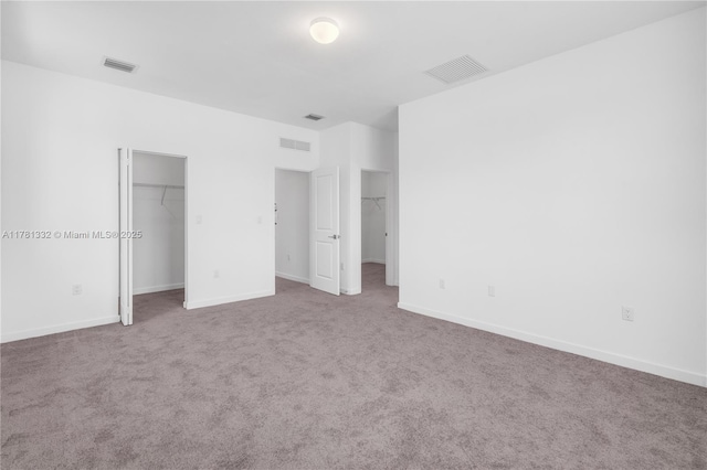 unfurnished bedroom featuring a spacious closet, carpet flooring, and visible vents