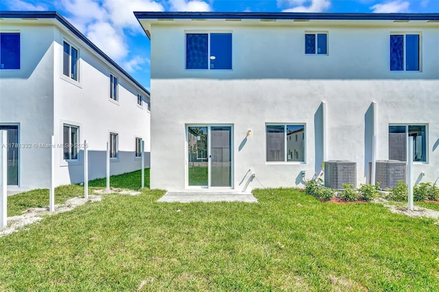 back of property with a yard, stucco siding, and central AC
