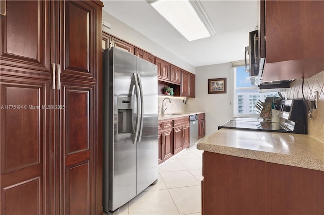 kitchen featuring light tile patterned floors, a sink, backsplash, appliances with stainless steel finishes, and light stone counters