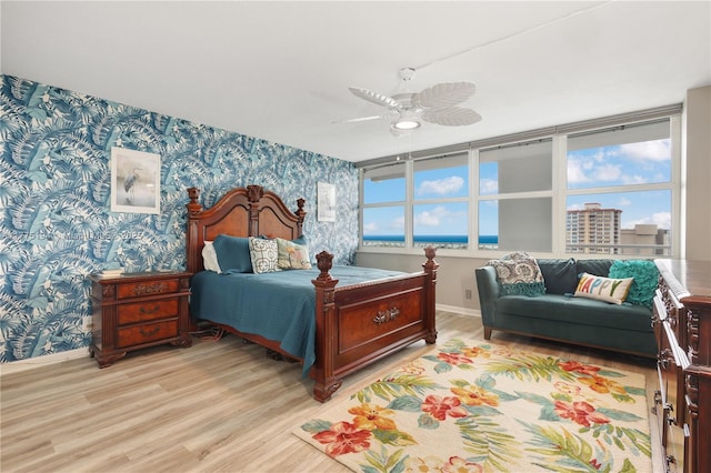 bedroom with baseboards, multiple windows, light wood-style floors, and wallpapered walls