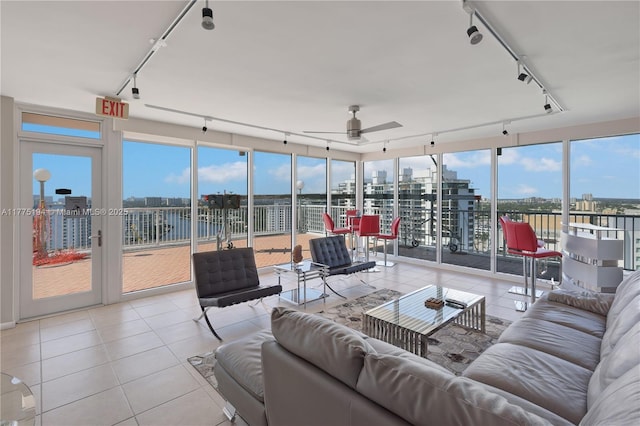 tiled living area with rail lighting, a water view, and ceiling fan